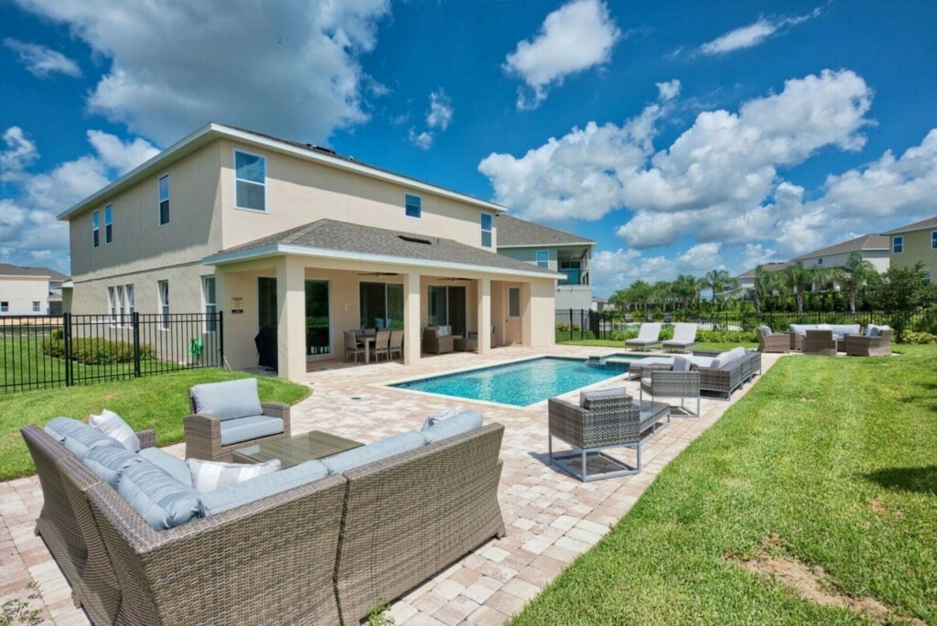 Una casa moderna con piscina, mobiliario exterior y un césped cuidado.