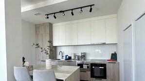 A modern kitchen with a central island, bar stools, and a dining area. - Bright, Spacious 3 Bedroom Penthouse in Vibrant Leslieville in Downtown Toronto (Toronto)