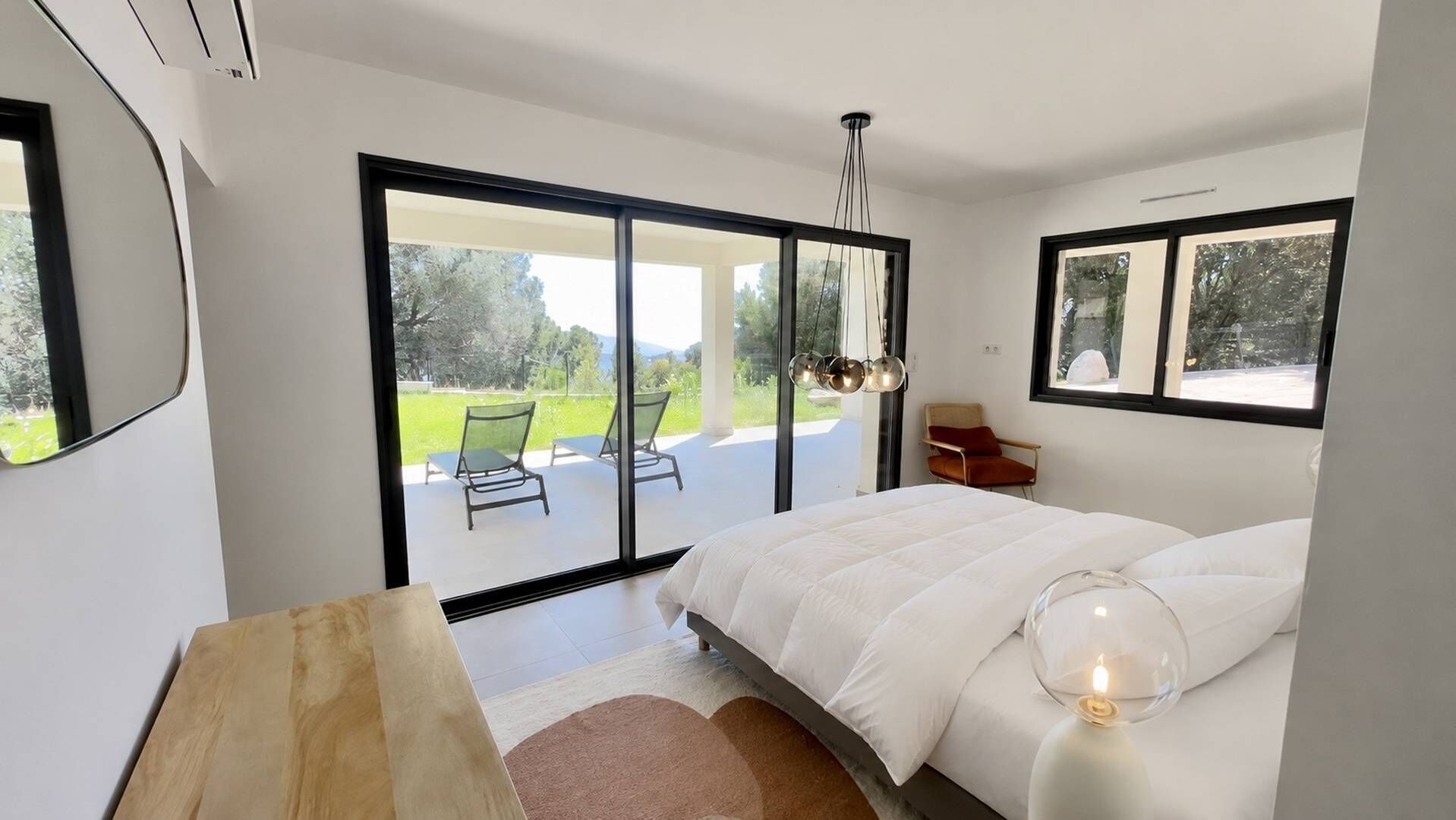 Une chambre moderne avec un grand lit, une table de chevet en bois et une lampe de chevet en verre.