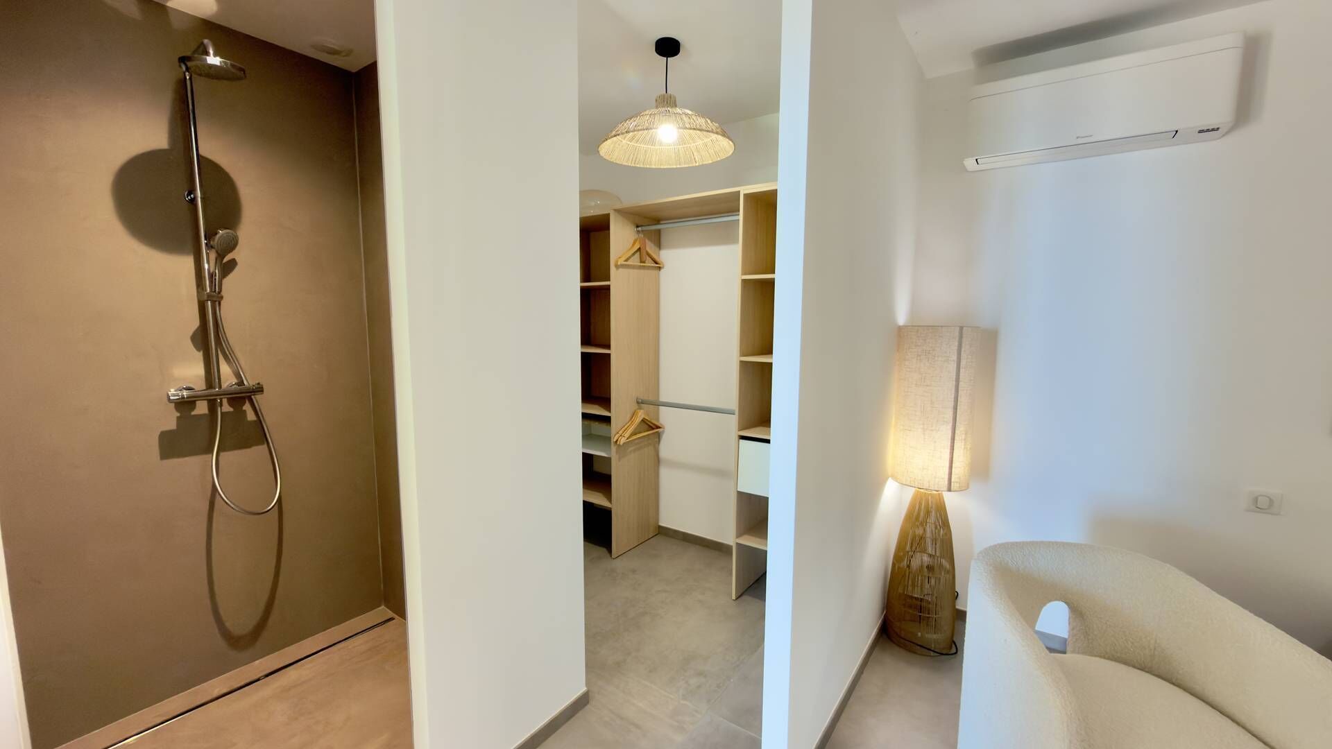 A bathroom with a shower, a hanging light fixture, and a wall-mounted air conditioner.