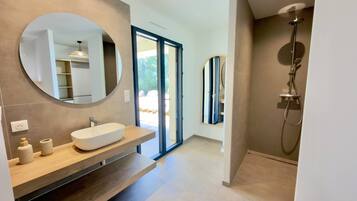Een moderne badkamer met een grote spiegel, een vrijstaand badkamermeubel en een douche.