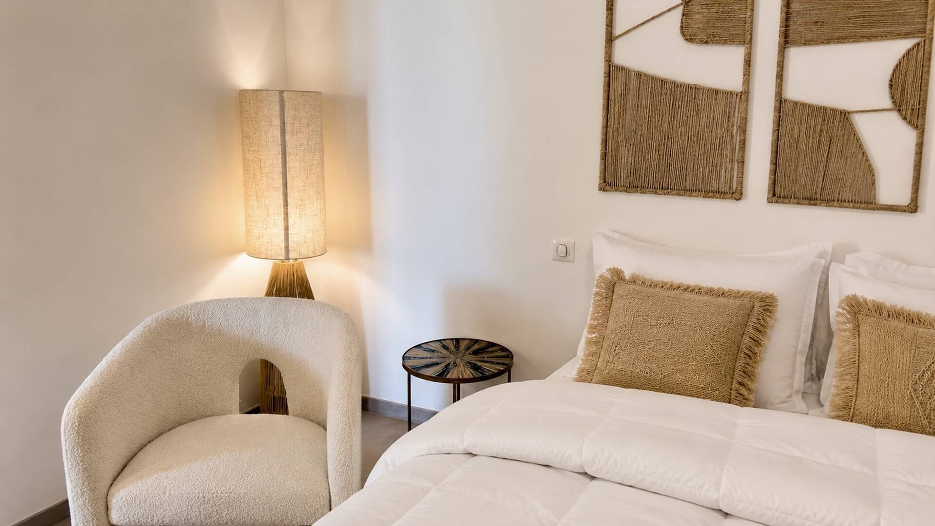 Une chambre à coucher avec un lit, une chaise, une lampe et des œuvres d’art murales.