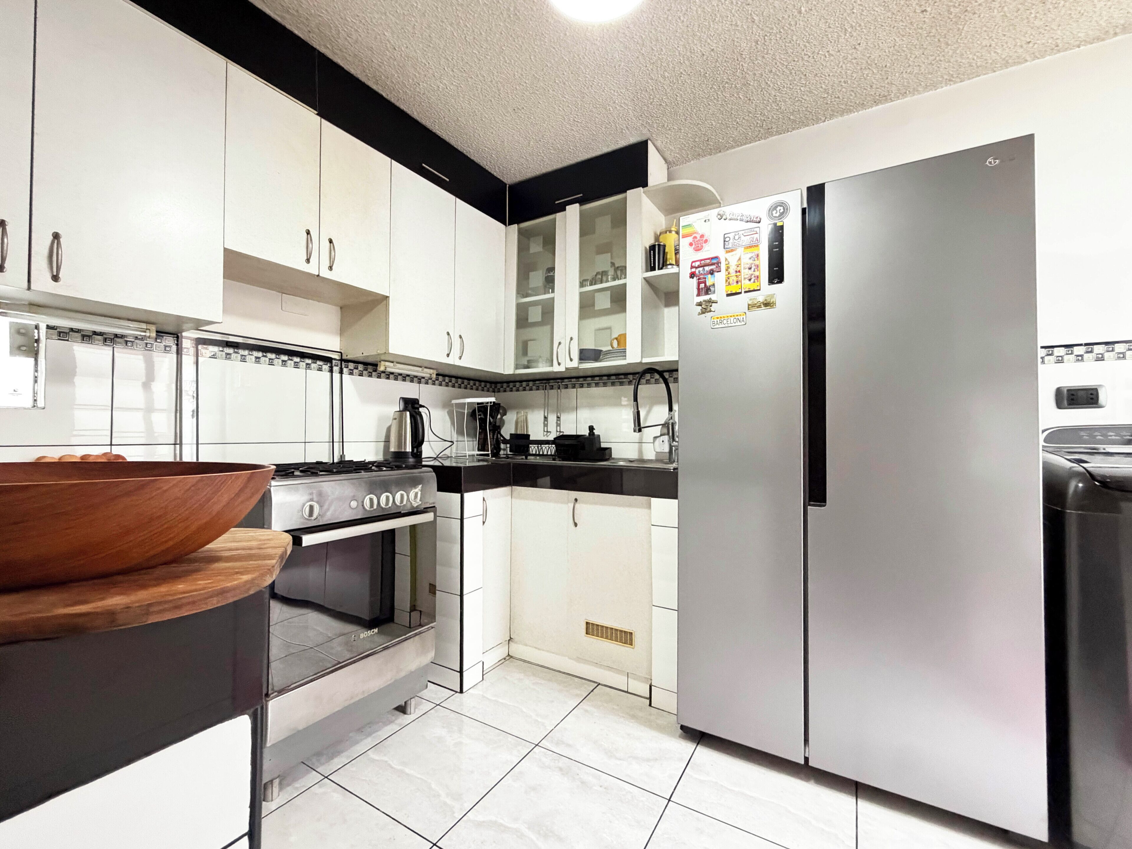 Una cocina moderna con armarios blancos, un refrigerador de acero inoxidable y un horno Bosch.