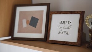 To billeder i rammer på en hylde, et med geometrisk design og et andet med et motiverende citat.
