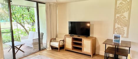 A modern living room with a flat-screen TV, a ceiling fan, a wooden entertainment unit, a sofa, and a coffee table.