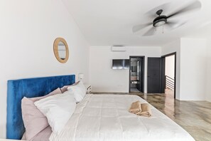 Ein Schlafzimmer mit einem Bett, einem Deckenventilator, einem Spiegel und einer Klimaanlage.