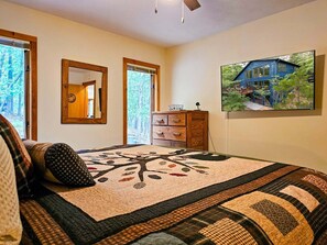 A bedroom with a large bed, a dresser, a mirror, and a painting of a house. - Bear Lodge - Hot tub & Bryce Mountain views! (Basye)
