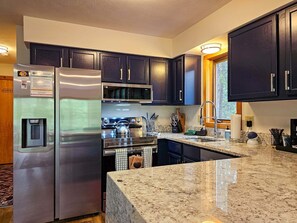 A modern kitchen with stainless steel appliances, dark cabinetry, and a granite countertop. - Bear Lodge - Hot tub & Bryce Mountain views! (Basye)