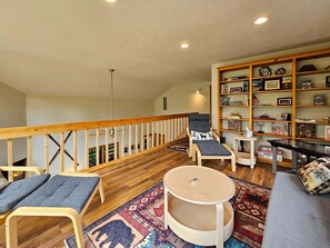 A cozy living area with a wooden staircase, a bookshelf, and a round table. - Bear Lodge - Hot tub & Bryce Mountain views! (Basye)