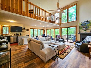 A spacious living area with a large sectional sofa, a dining table, and a kitchen in the background. - Bear Lodge - Hot tub & Bryce Mountain views! (Basye)