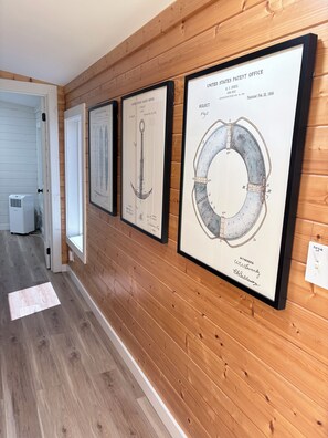 A hallway with framed patent documents on the wall, a door, and a white air conditioning unit.