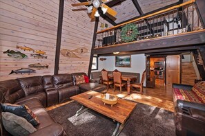 Een ruime woonkamer met een leren bank, een houten salontafel en een eethoek met stoelen en een tafel.