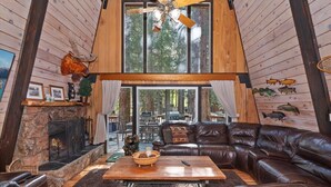 Ein gemütliches Blockhaus-Interieur mit Kamin aus Stein, Ledersofa und Deckenventilator.