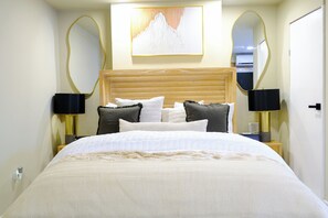A neatly arranged bedroom with a large bed, two bedside tables, and a wall-mounted mirror. - Walk to the Beach Ocho Rios Apartment (Ocho Rios)