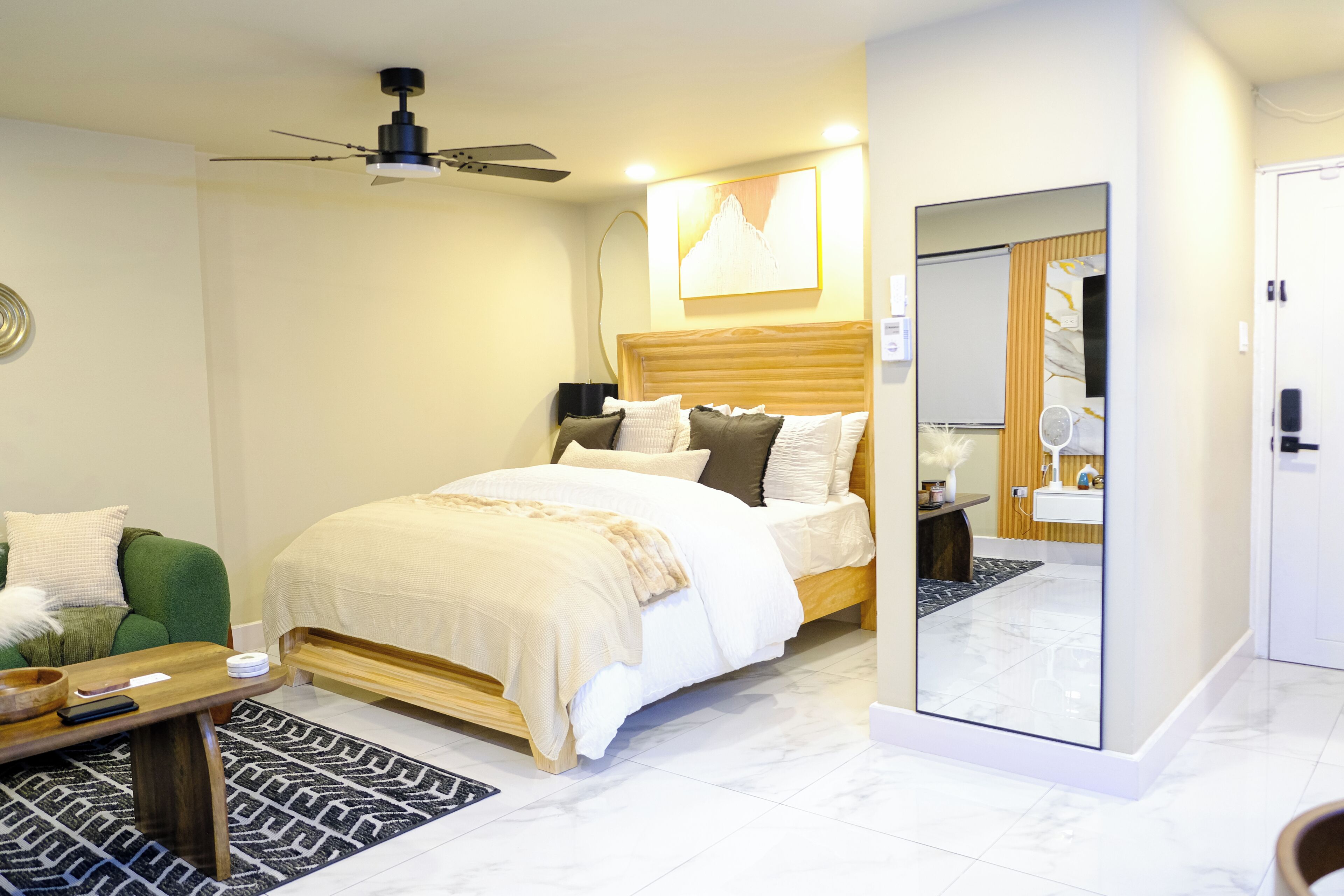 A modern bedroom with a bed, bedside table, and a mirror.