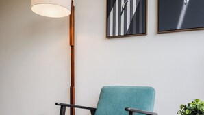 Et moderne værelse med en lysegrøn polstret stol, et rundt bord med en rød genstand og en gulvlampe.