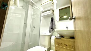 A bathroom with a white toilet, a sink, a towel rack, and a shower area. - Fátima Hotel (Medellín)
