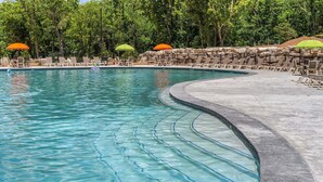 Una piscina con agua cristalina, rodeada de sillas de descanso y sombrillas.