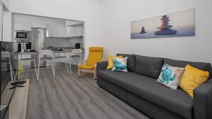A modern living room with a grey sofa, yellow and blue pillows, a yellow armchair, and a painting of stacked stones on the wall. - Funchal Oh My! - Cozy Stay with Terrace (Funchal)