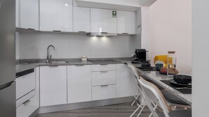A modern kitchen with white cabinets, a stainless steel sink, and a built-in stove. - Funchal Oh My! - Cozy Stay with Terrace (Funchal)