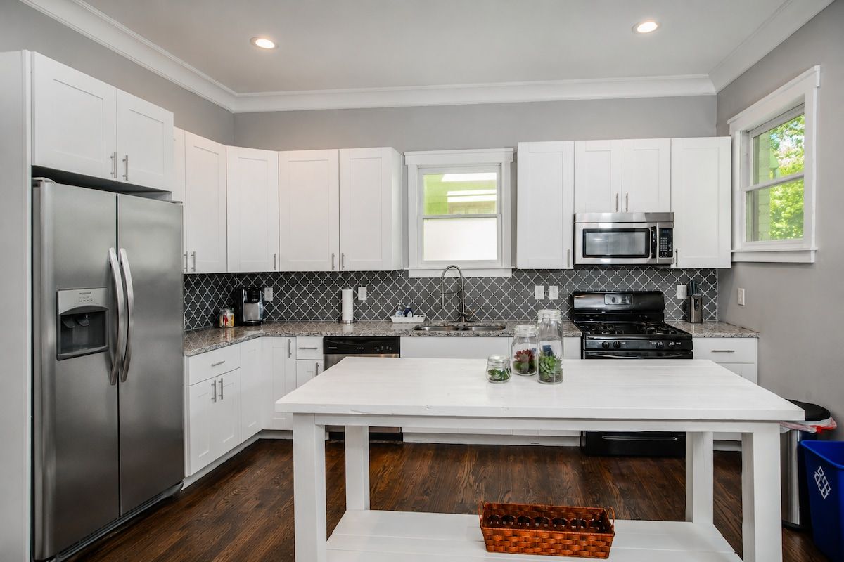 A modern kitchen with white cabinets, stainless steel appliances, and a central island.