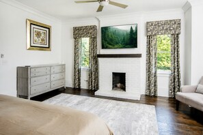 A bedroom with a fireplace, a bed, a dresser, and a television. - Spacious 3BR Home with Soaking Tub Near Downtown and Stadium in Atlanta (Atlanta)