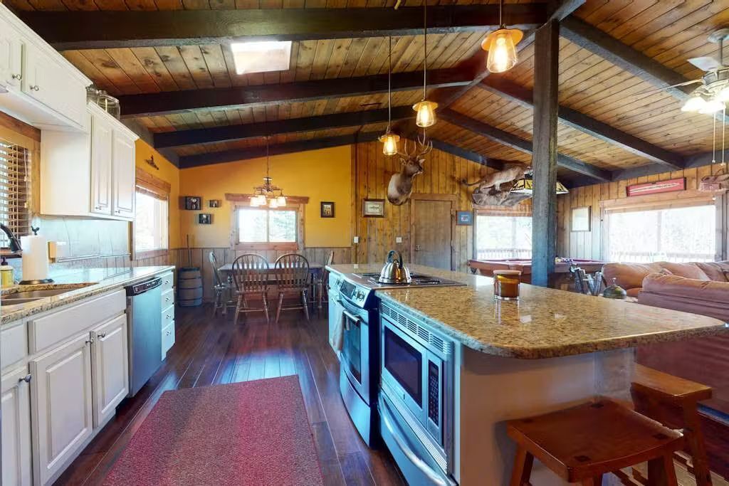 A kitchen with wooden beams, granite countertops, and a central island with seating.