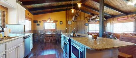 A kitchen with wooden beams, granite countertops, and a central island with seating.
