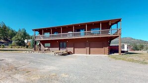 A two-story log cabin with a balcony, a garage, and a gravel driveway. - 4 Eagles | Hot Tub | South Fork Cabin | Wolf Creek (South Fork)