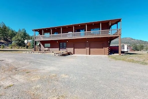 Eine zweistöckige Blockhütte mit Balkon, Garage und einem Schotterweg.
