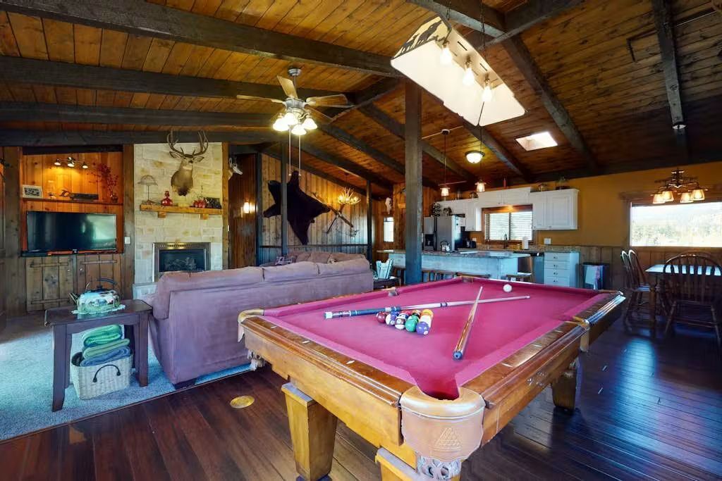 A pool table in a room with wooden floors and a ceiling fan.