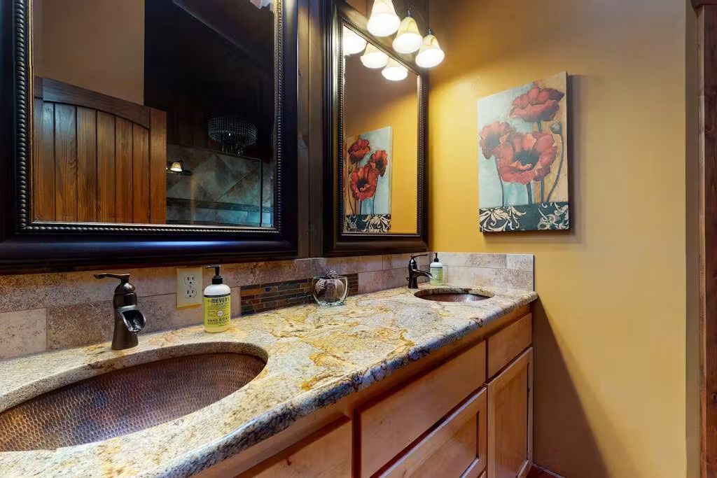 Un baño con lavamanos doble, un espejo grande y un cuadro de flores en la pared.