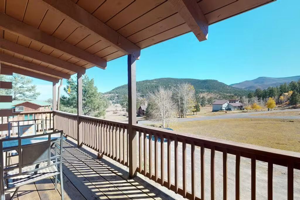 A wooden balcony with a view of a residential area and mountains.