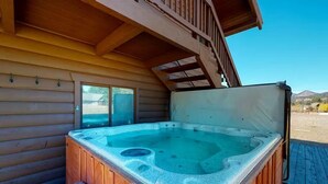 A hot tub outside a wooden cabin with a wooden deck and a clear sky in the background. - 4 Eagles | Hot Tub | South Fork Cabin | Wolf Creek (South Fork)