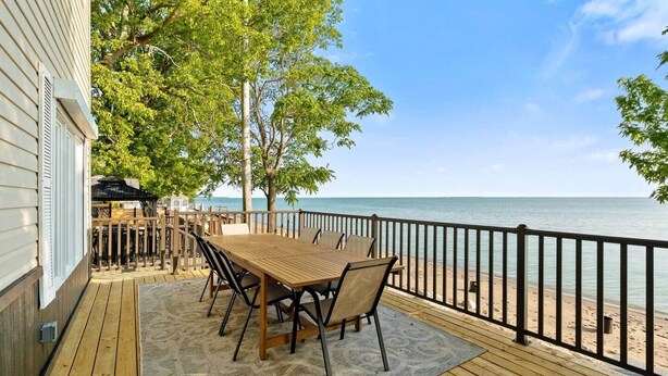 Een houten terras met een tafel en stoelen, met uitzicht op een strand.