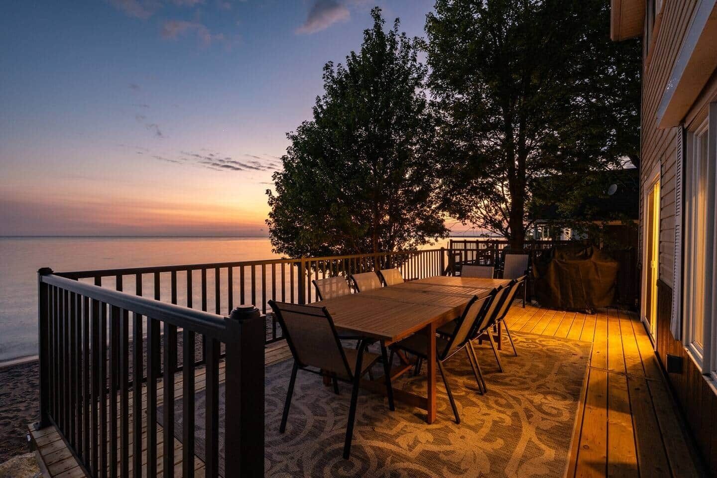 Un espace extérieur aménagé pour les repas, avec vue sur la mer, une terrasse en bois et une rambarde.