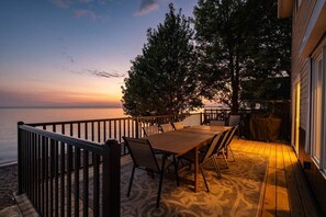 An outdoor dining area with a view of the sea, a wooden deck, and a railing.