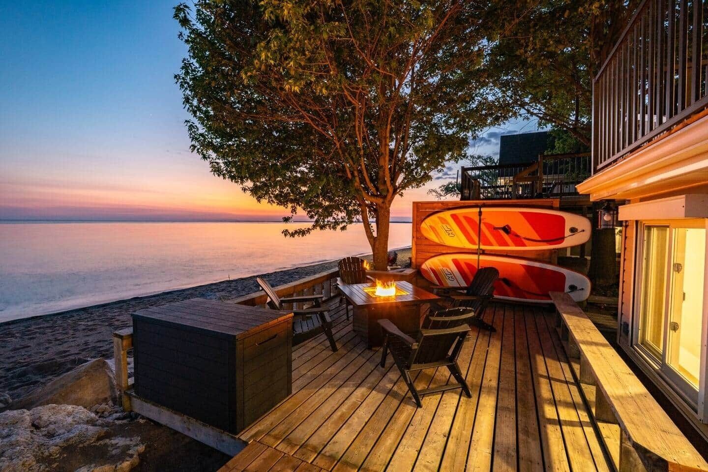 A wooden deck with a fire feature, seating, and surfboards.