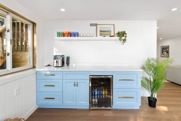 A kitchen with a blue island, white upper cabinets, and a built-in refrigerator.