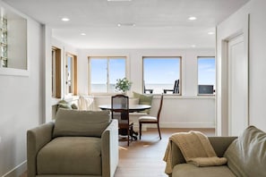 A modern living room with a dining area, large windows, and a view of the sea. - Beachfront Cottage w/ Sauna Steps to Point Pelee National Park (Leamington)