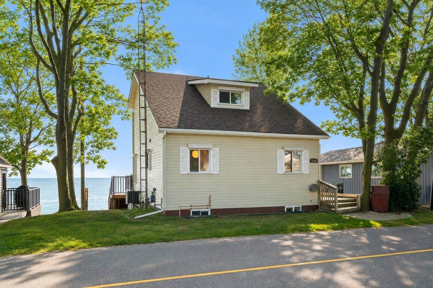 A single-story house with a gabled roof, a small porch, and a view of the water.