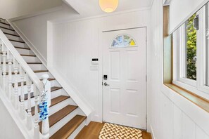 A staircase with white balusters and wooden steps leading to a white door with a window above it.