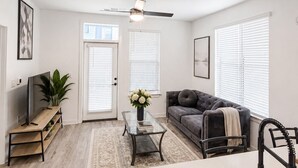 Una sala de estar moderna con sofá, mesa de centro y mueble para la televisión.