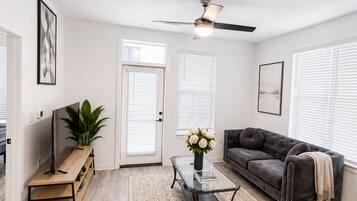 A living room with a ceiling fan, a sofa, a coffee table, and a TV on a wooden stand.