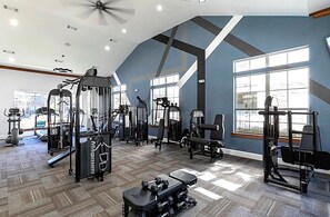 A gym with various exercise equipment, large windows, and a high ceiling. - Resort-Style 1BR Pool, Gym & Movie Theater (Conroe)