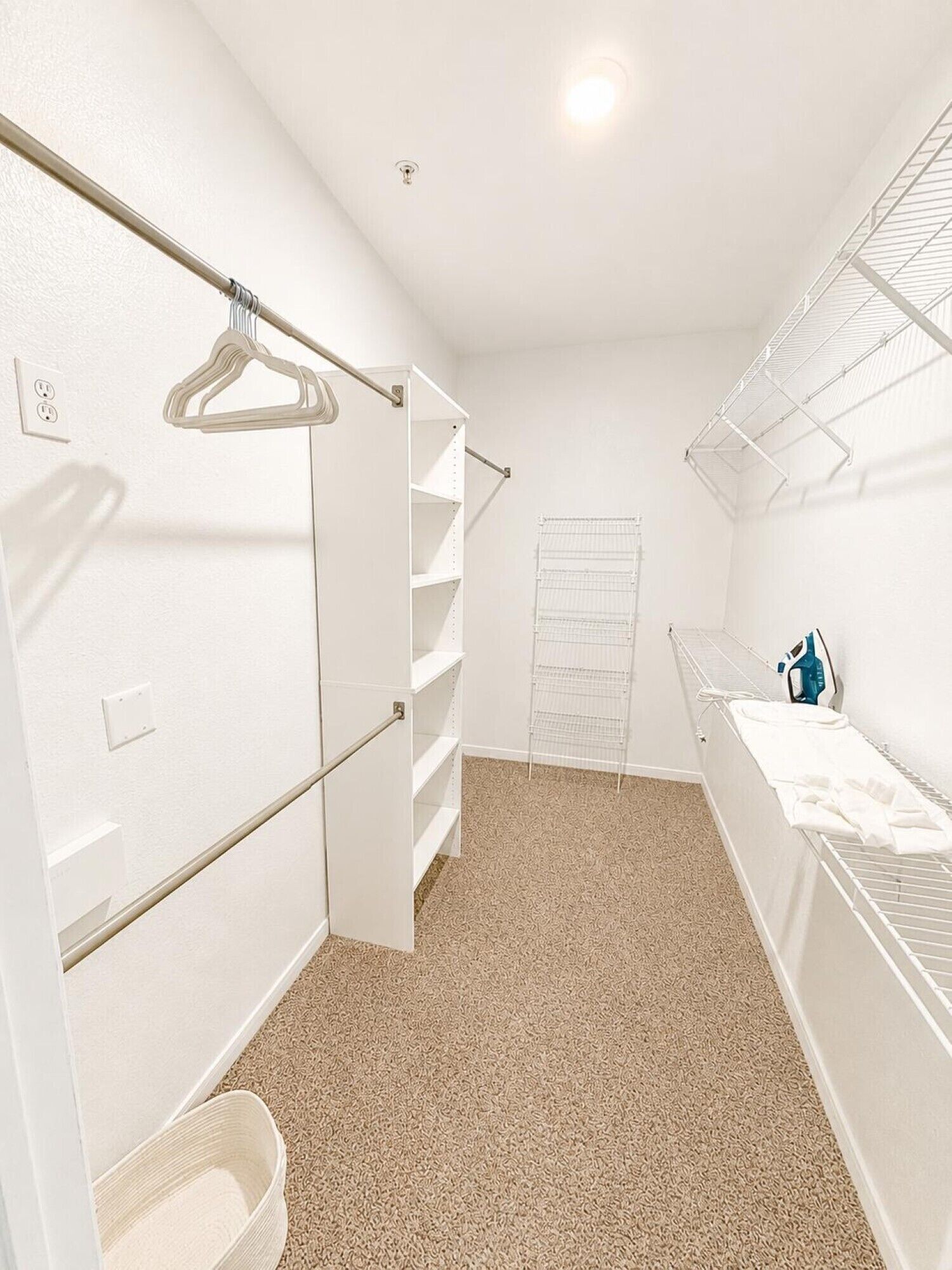 A walk-in closet with a hanging rod, shelves, and a drying rack.