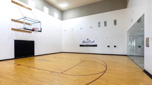 En basketballbane med trægulv, en basketballkurv og et skilt for Stone Creek Premier Apartments.