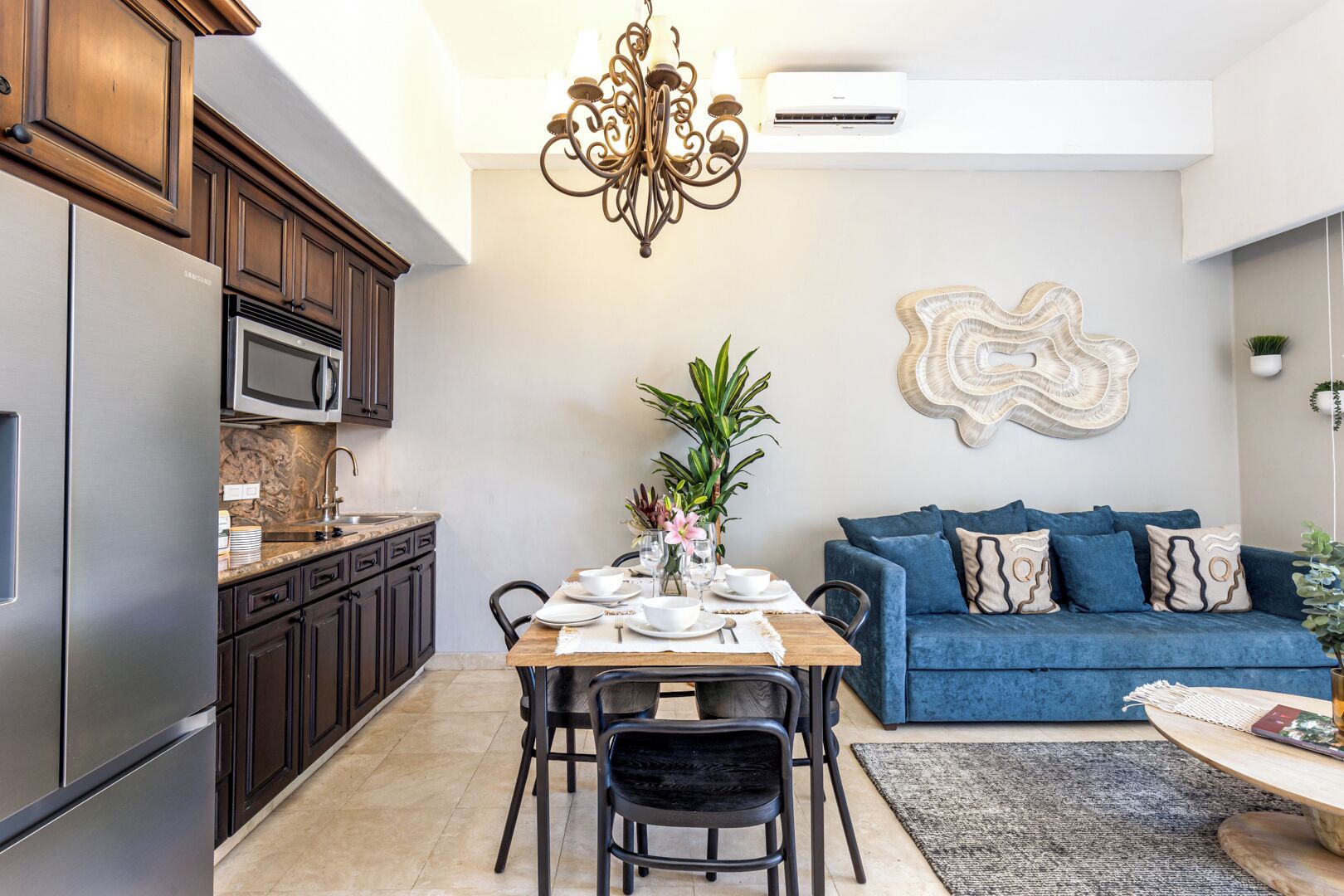 Una cucina moderna con zona pranzo, un divano blu e un elemento decorativo a parete.