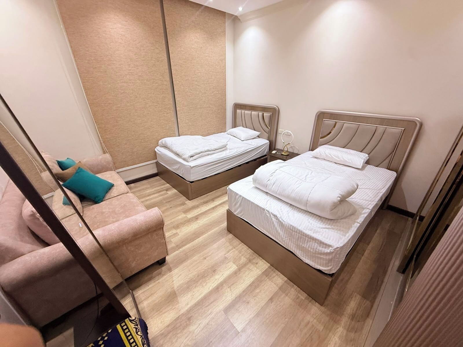 Une chambre d’hôtel avec deux lits, un canapé et un miroir.