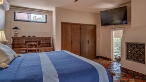 Una camera da letto con un letto grande, un settimino in legno, una televisione fissata al muro e un pavimento decorato con un motivo in pietra.